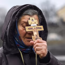 A religious woman holds a cross as she prays in Kyiv's Independence Square on Feb. 24, 2022.
