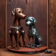 A metal dog statues on a wood surface.